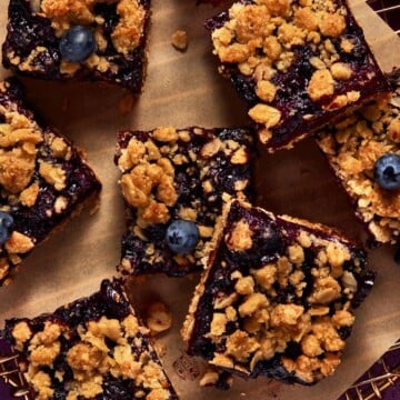 Blueberry Oat Crumble Bars cut into squares on a piece of brown parchment paper.
