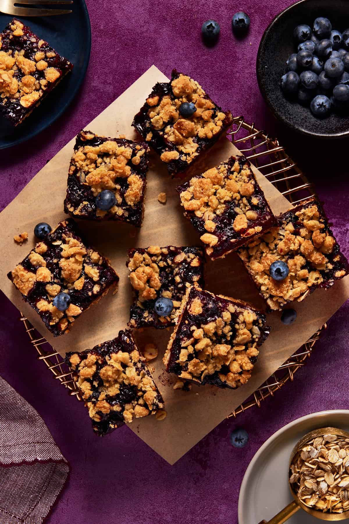 Blueberry Oat Crumble Bars on brown parchment paper on metal cooling rack. 