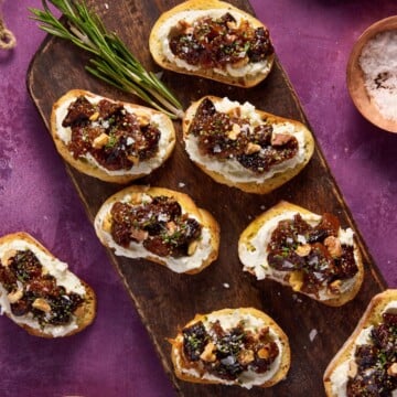 Fig & goat cheese crostini on a dark wood serving board.