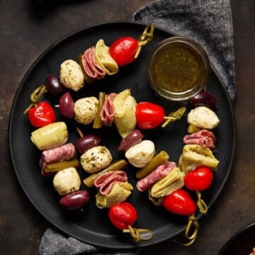 Antipasto Skewers on plate with dipping sauce.