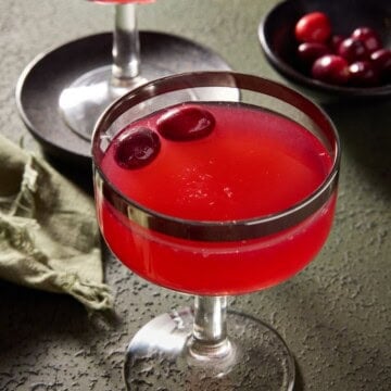 cranberry vodka gimlet in a coupe glass with a silver rim.