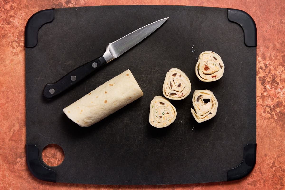 Rolled up tortillas sliced on cutting board.