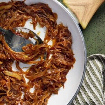 Caramelized onions in a pan with a green towel.